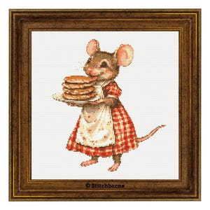 May include: A framed cross-stitch of a mouse holding a plate of pancakes. The mouse wears a red and white checkered dress and apron. The frame is a dark brown color. The image is from Stitchborne.