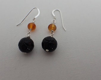Dangle earrings with onyx and amber on sterling silver earwires. The onyx has a flower carved into the bead.