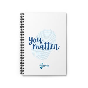 以下が含まれることがあります： 「you matter」という青い文字が書かれた白いリング綴じノート。テキストの後ろには、水色の指紋のデザインがあります。ノートには、青色の「clarity」ロゴも表示されています。