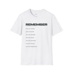 May include: White t-shirt with the word "REMEMBER" in dark gray block letters. Below the word "REMEMBER" are the phrases "you are worthy", "you are loved", "you are enough", "you are smart", "you are growing", "you are strong", and "you are important".