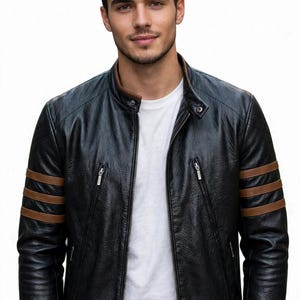 May include: A black leather jacket featuring a mandarin collar, a central zipper closure, and two diagonal zippered chest pockets. The sleeves are accented with three horizontal brown stripes, and the hem is finished with a brown band.