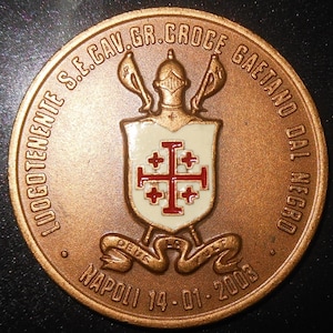 Peut inclure: Une médaille commémorative circulaire de couleur bronze avec un écusson central blanc orné d'une croix de Jérusalem rouge. Au-dessus de l'écusson se trouve un casque flanqué de deux épées. Le texte indique LUOGOTENENTE S.E.CAV.GR.CROCE GAETANO DAL NEGRO et NAPOLI 14-01-2003.