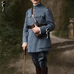 May include: A vintage military uniform in a muted blue-gray color. The uniform features a high collar, gold buttons, and a brown leather belt and shoulder strap. The trousers have a dark stripe down the side, and the boots are brown. A walking stick is held in one hand.