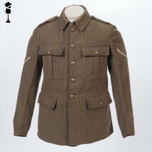 May include: A brown military jacket with four front pockets and gold-colored buttons. The jacket has shoulder epaulets and a sergeant's chevron on the left sleeve. The collar is a classic notched style. The jacket is displayed on a white mannequin.