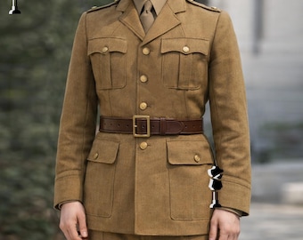May include: A tan military uniform consisting of a jacket, trousers, and a brown leather belt. The jacket has four front pockets, gold buttons, and shoulder epaulets. The belt has a gold buckle. The uniform is made of a textured fabric.