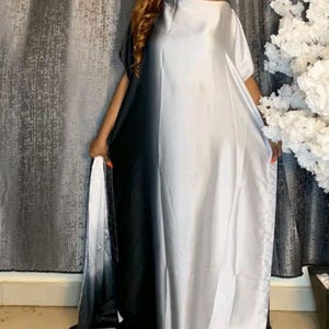以下が含まれることがあります： オフショルダーのロングドレスで、カラーブロックのデザインです。ドレスは縦に分割され、片側は黒、もう片側は白から黒に移行しています。生地は滑らかでシルクのような素材のようです。