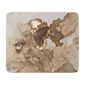 Könnte beinhalten: Ein quadratisches, cremefarbenes Mauspad mit einem Aquarelldesign. Das Design zeigt braune und goldene abstrakte Formen, die Tintenklecksen und metallischen Akzenten ähneln. Die Kanten sind sauber vernäht.