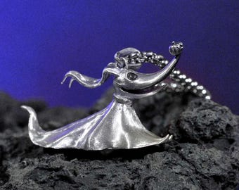 May include: A silver-toned metal pendant shaped like a ghost dog with long ears, a wide mouth, and a small pumpkin on its nose. The pendant is attached to a silver-toned metal chain, featuring a smooth, reflective surface and a flowing, skirt-like base.
