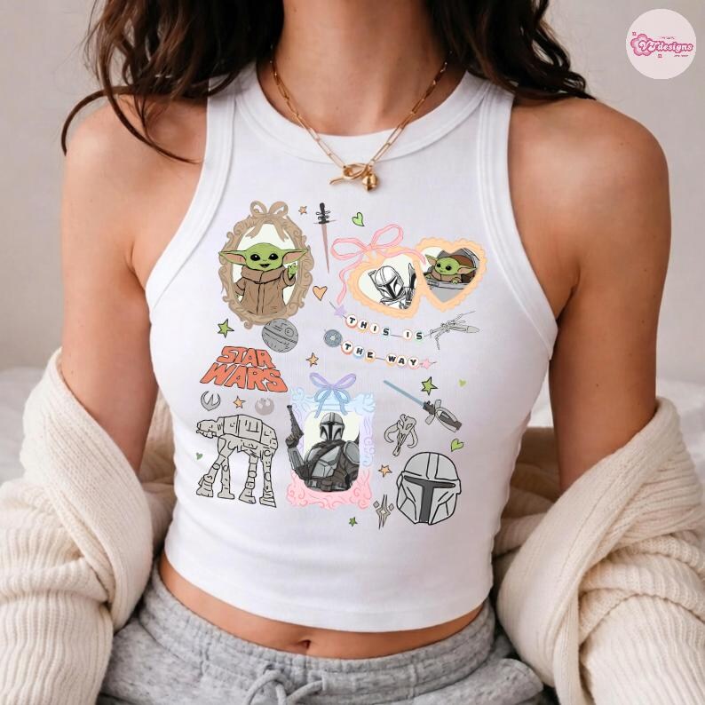 May include: White tank top featuring Star Wars-themed graphics, including Grogu, the Mandalorian, and the text "THIS IS THE WAY." The design incorporates various illustrations and text elements in a colorful arrangement.