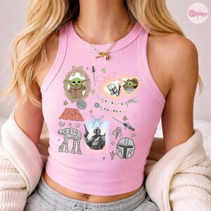 May include: Pink crop top with Star Wars themed graphics. Features images of Grogu, the Mandalorian, and the text "This is the Way." Includes various Star Wars symbols and characters.