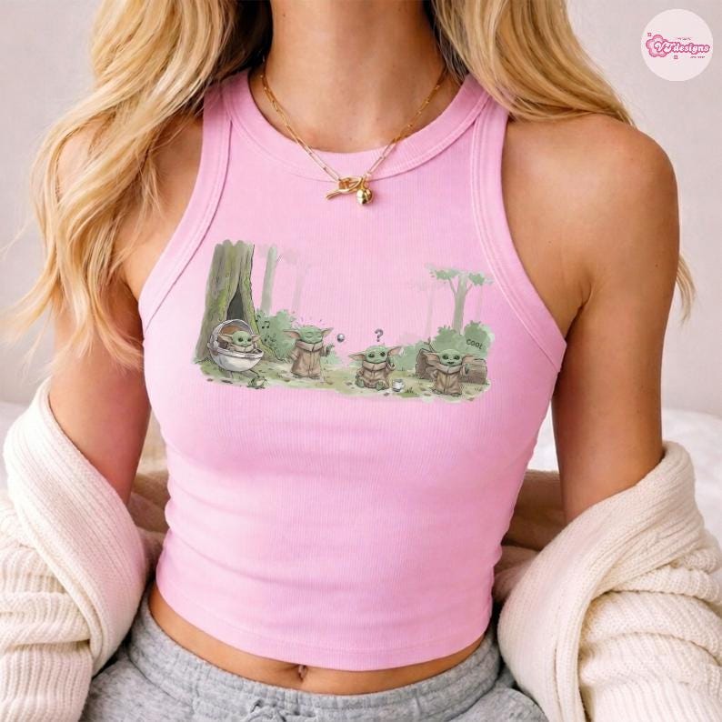 May include: Pink tank top with a graphic of Grogu from The Mandalorian. The illustration shows Grogu in a forest setting with other characters. The tank top is sleeveless and has a ribbed texture.