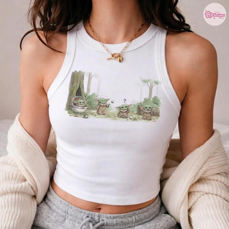 May include: White tank top featuring a colorful illustration of Grogu from The Mandalorian. The graphic shows Grogu in various poses in a forest setting. The tank top is sleeveless and has a round neckline.