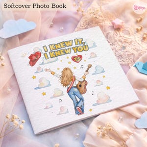 May include: A square softcover photo book featuring a white cover with a central illustration of a person with long hair playing an acoustic guitar. The text reads I KNEW IT, I KNEW YOU with a red cowboy hat, a heart labelled TS, stars, and clouds.