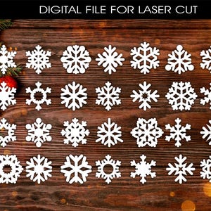 Pode incluir: Uma coleção de designs de flocos de neve brancos para corte a laser, exibidos em um fundo de madeira. A imagem inclui várias formas de flocos de neve e o texto "DIGITAL FILE FOR LASER CUT".