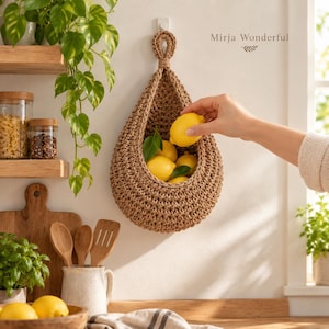 May include: A teardrop-shaped hanging basket made of thick, brown woven cord, suspended from a wall hook. The basket contains several bright yellow lemons with green leaves. The text Mirja Wonderful is printed on the wall above the basket.