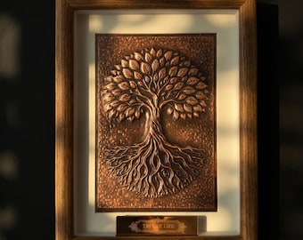 May include: A framed copper-colored relief sculpture of a tree with a detailed root system and leafy branches. The artwork is set against a white matting and framed in a wooden frame. A small rectangular plaque at the bottom reads "TREE OF LIFE."