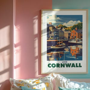 May include: A framed poster with a vintage travel illustration of a harbor scene in Looe, Cornwall. The poster has a blue, green, and white color scheme and features a sailboat in the foreground.