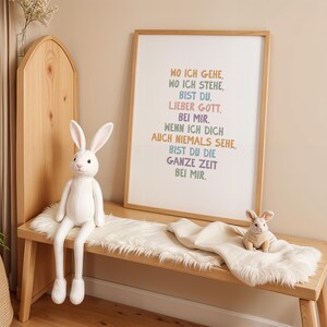 May include: A wooden bench with a white faux fur throw and two stuffed rabbits. A framed print with German text hangs above the bench. The text is in various colors. The room has a neutral color palette.