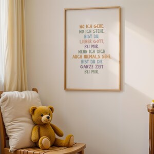 May include: A framed print with the text "WO ICH GEHE, WO ICH STEHE, BIST DU, LIEBER GOTT, BEI MIR, WENN ICH DICH AUCH NIEMALS SEHE, BIST DU DIE GANZE ZEIT BEI MIR." A brown teddy bear sits on a wooden chair next to a white pillow.