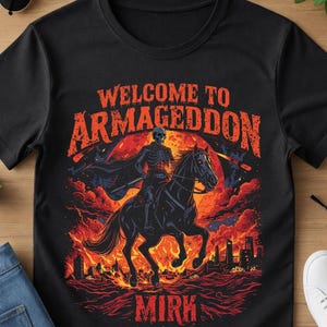 Puede incluir: Camiseta negra con un diseño gráfico de un jinete esqueleto sobre un caballo negro, ambientado en una escena apocalíptica en llamas. El texto "WELCOME TO ARMAGEDDON" está arriba, con "MIRK" debajo.