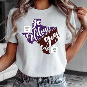 May include: White t-shirt featuring a purple and maroon Texas-shaped graphic with the words "Go Wildcats" and "Gig 'Em". The shirt also includes the text "House Divided" and logos for Abilene "ACU" and Texas "A&M".