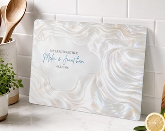 May include: A rectangular glass cutting board featuring a pearlescent white and cream marbled pattern. The center displays the text 30 YEARS TOGETHER, the names Melia & Jonathan in blue script, and the date 08.12.1996 in black text.