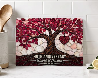 May include: A rectangular glass cutting board featuring a stained-glass style tree with deep red leaves and a heart-shaped ornament. The text reads 40TH ANNIVERSARY, David & Jessica, and MAY 25 2026, printed in white against the dark brown tree roots.