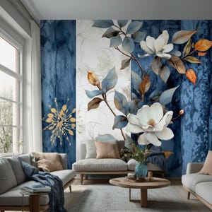 Peut inclure: Un salon avec une peinture murale florale représentant de grandes fleurs de magnolia blanches, des feuilles bleues et des accents orange et dorés. La peinture murale est sur un mur à rayures bleues et blanches. La pièce comprend des canapés gris, une table basse en bois et un tapis.
