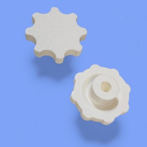 May include: Two white, star-shaped knobs with a textured surface. One knob is viewed from the top, and the other is viewed from the side, revealing a cylindrical post. The knobs are set against a light blue background.
