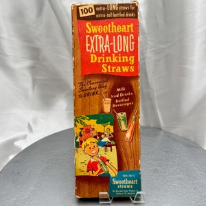 May include: A rectangular cardboard box of Sweetheart Extra-Long Drinking Straws. The box features a wood-grain pattern, a red banner with yellow text, and a cartoon illustration of a person drinking from a straw. It states 100 extra-long straws.