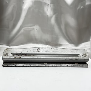 May include: A vintage silver-toned Muther Adjustable Punch No. 20, Made in USA. The punch features a ruler along the bottom edge and the letter "M" on each end. The text "Patents Pending" is also visible.