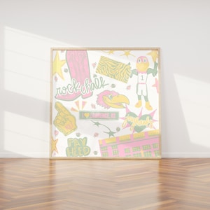 May include: A square framed art print featuring a collage of illustrations in pink, yellow, and green. Elements include a pink cowboy boot, a yellow foam finger, a bird mascot, a stadium, and text reading rock chalk, pay heed, and I love Lawrence KS.