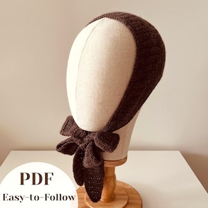May include: A dark brown knitted headband with a bow detail, displayed on a mannequin head. The headband is made of a textured yarn. The text "PDF Easy-to-Follow" is visible in the image.