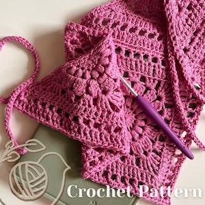 Puede incluir: Primer plano de un patr&oacute;n de crochet rosa con un gancho de crochet. El patr&oacute;n es un cuadrado con un dise&ntilde;o de flor en el centro. El texto "Crochet Pattern" es visible en la parte inferior de la imagen.