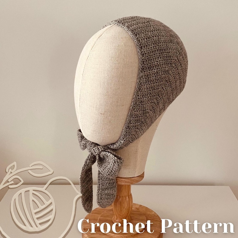 May include: A grey crocheted bonnet, displayed on a mannequin head. The bonnet has a textured stitch pattern and ties under the chin with a bow. The words "Crochet Pattern" are visible at the bottom of the image.