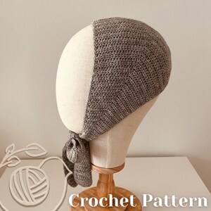 May include: A grey crocheted head covering, shown on a mannequin head. The head covering has a textured design and a tie closure. The words "Crochet Pattern" are visible at the bottom of the image.