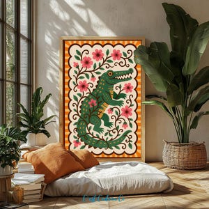 Könnte beinhalten: Ein rechteckiger gerahmter Kunstdruck mit einem grünen Alligator, umgeben von rosa Blumen und dunkelgrünen Ranken auf cremefarbenem Hintergrund, eingefasst von einer gewellten Bordüre und einem äußeren Rahmen aus orangefarbenen und cremefarbenen vertikalen Streifen.