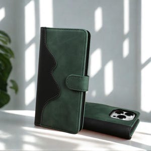 May include: A green and black leather phone case with a magnetic clasp. The case has a two-tone design, with a wavy black accent on the left side. A matching phone case is visible in the background.