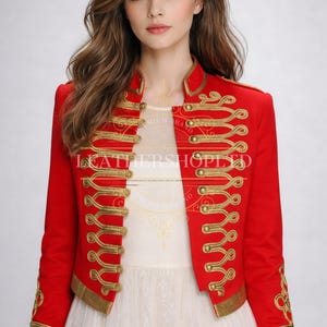May include: A red jacket with gold trim and elaborate gold embroidery. The jacket features a high collar and decorative gold buttons. The long sleeves also have gold embroidery. The jacket is open at the front, revealing a white garment. The text "LEATHERSHOP LTD" is visible.