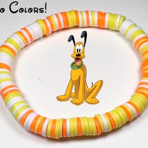 Puede incluir: Una pulsera colorida con un diseño inspirado en Pluto. La pulsera está hecha de cuentas planas y redondas en blanco, amarillo y naranja. La imagen también incluye una ilustración de dibujos animados de Pluto.