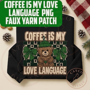 May include: Black sweatshirt with a faux yarn patch featuring a teddy bear wearing a green hat and bow tie. The text "COFFEE IS MY LOVE LANGUAGE" is displayed above and below the bear. The sweatshirt has long sleeves.