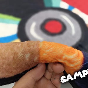 May include: Close-up of a section of a colorful rug with a brown and orange design. The word "SAMPLE" is printed in white across the bottom right corner of the image.