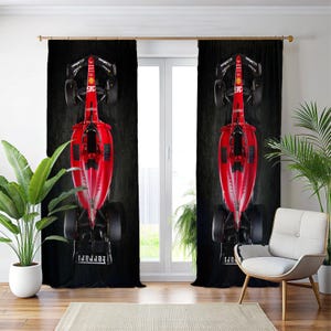 May include: Red Formula 1 race car curtains. The curtains feature a top-down view of a red race car with black wheels and accents. The curtains are set against a dark background, creating a dramatic contrast. The Ferrari logo is visible.
