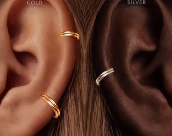 May include: Two double-banded ear cuffs are displayed on ears. The left ear features two gold-toned double-banded ear cuffs, labeled with the text GOLD. The right ear features one silver-toned double-banded ear cuff, labeled with the text SILVER.