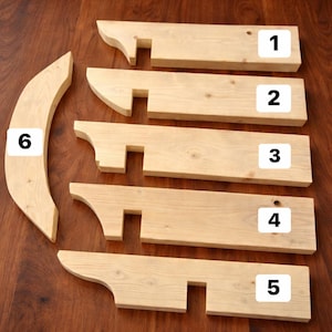 May include: Six unfinished light-colored wooden components for assembly. Five rectangular boards labeled 1 through 5 feature a curved end and a square notch. One curved, crescent-shaped piece is labeled 6. The wood grain is visible throughout.