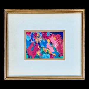Pode incluir: Pintura abstrata com moldura dourada. A obra apresenta uma vibrante mistura de cores, incluindo vermelho, azul, rosa e amarelo, aplicadas com pinceladas visíveis. A pintura está emoldurada com um passe-partout branco.