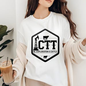 May include: White t-shirt with a black and white graphic. The graphic is a hexagon shape with the letters "CTT" and the words "OIL EXPLORATION & CATTLE". The design includes an oil derrick and cow silhouettes.