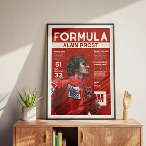 May include: Framed poster of Alain Prost in a red racing suit. The poster has the text "FORMULA ALAIN PROST" and statistics like 51 pole positions and 33 wins. The poster is on a wooden cabinet with a plant and a wooden hand sculpture.