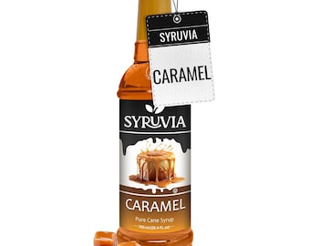 Pode incluir: Uma garrafa de vidro de xarope de caramelo com um rótulo castanho que diz "SYRUVIA CARAMEL Pure Cane Syrup 750 ml (25.4 FL oz)". Há caramelos em primeiro plano.