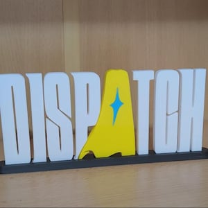 Puede incluir: Un letrero impreso en 3D que deletrea la palabra "DISPATCH" en letras blancas. La letra "A" es reemplazada por una forma amarilla con un diseño de estrella azul. El letrero se asienta sobre una base negra.